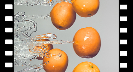 Oranges are flying with a jet of water, slow motion